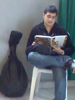 A teenage Majed seated with his oud beside him