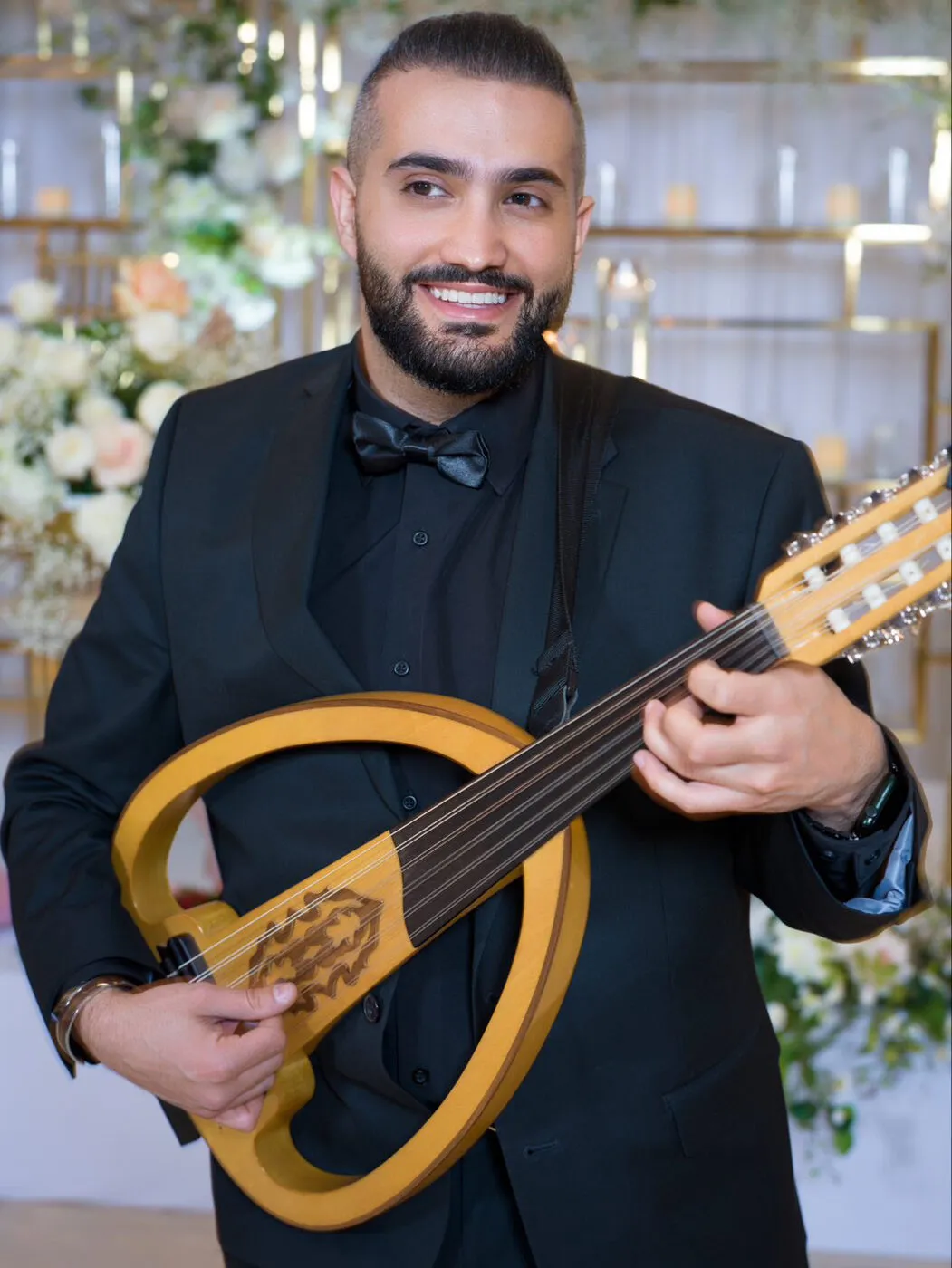 Majed in black tie beside a floral installation at a wedding